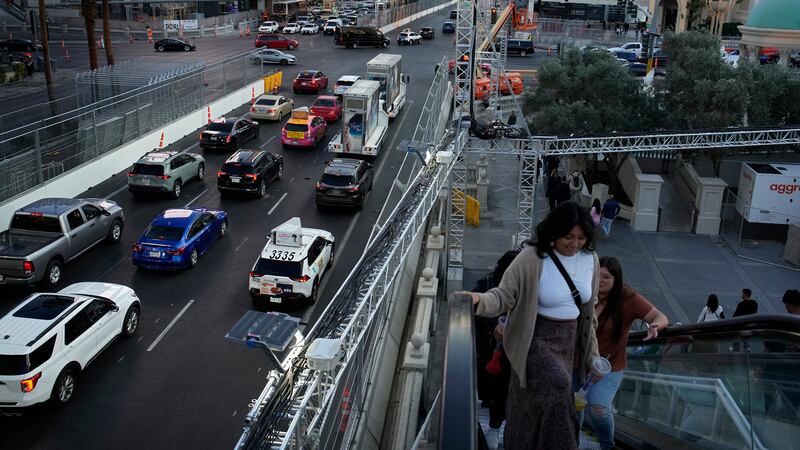 Pedestrians take an escalator along the Las Vegas Strip beside rigging and fencing installed...