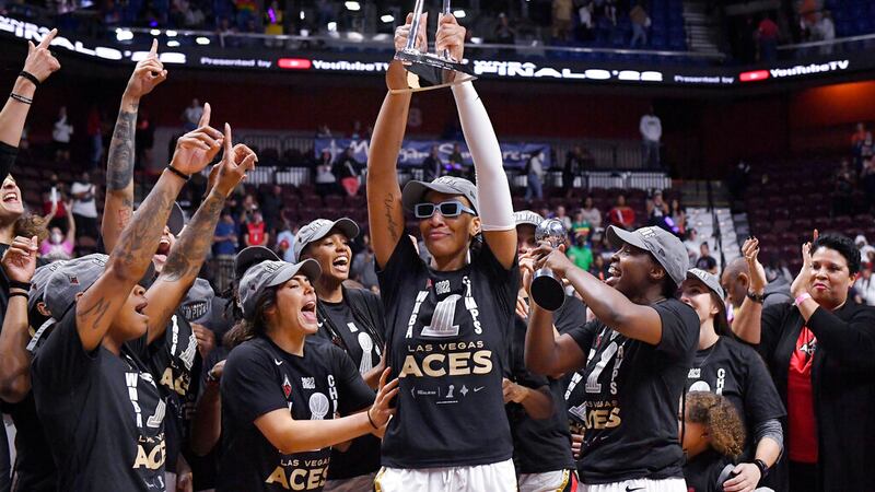 Las Vegas Aces' A'ja Wilson holds up the championship trophy as she celebrates with her team...