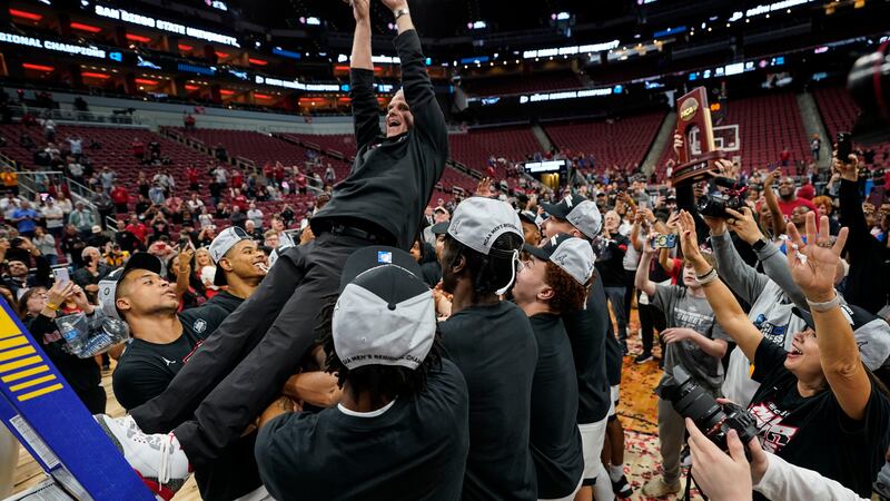 San Diego State head coach Brian Dutcher holds the remains of the net and is falls into the...