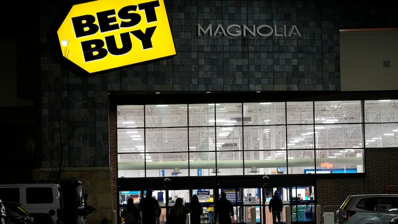 FILE - Shoppers are silhouetted as they walk toward a Best Buy store after doors opened at 5...