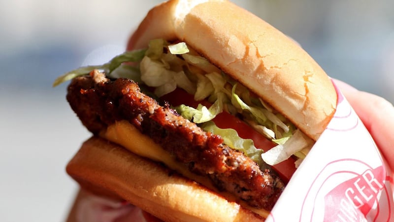 FILE -- A woman prepares to take a bite out of a cheeseburger. The sandwich from Fatburger is...