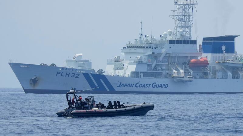 FILE - A Philippine Coast Guard rigid hull inflatable boat passes by the Japanese Coast Guard...